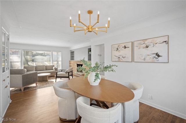 dining room with hardwood / wood-style floors, a chandelier, and a fireplace