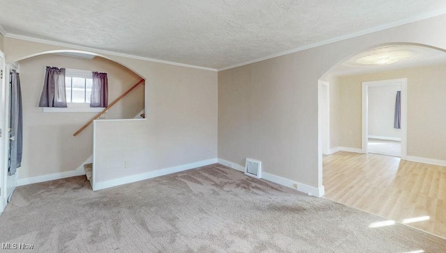 carpeted spare room featuring a textured ceiling and crown molding