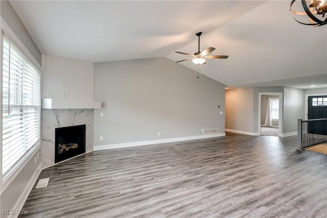 921 Cabot Dr, Canal Fulton, OH 44614 - unfurnished living room featuring a ceiling fan, wood finished floors, a premium fireplace, baseboards, and vaulted ceiling