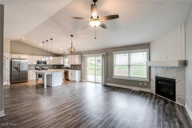 921 Cabot Dr, Canal Fulton, OH 44614 - unfurnished living room with vaulted ceiling, dark wood-style flooring, a premium fireplace, a ceiling fan, and baseboards