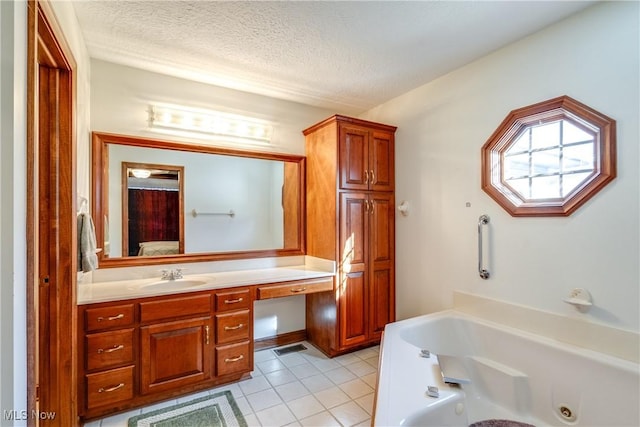 bathroom featuring a textured ceiling, a bathing tub, vanity, and tile patterned flooring