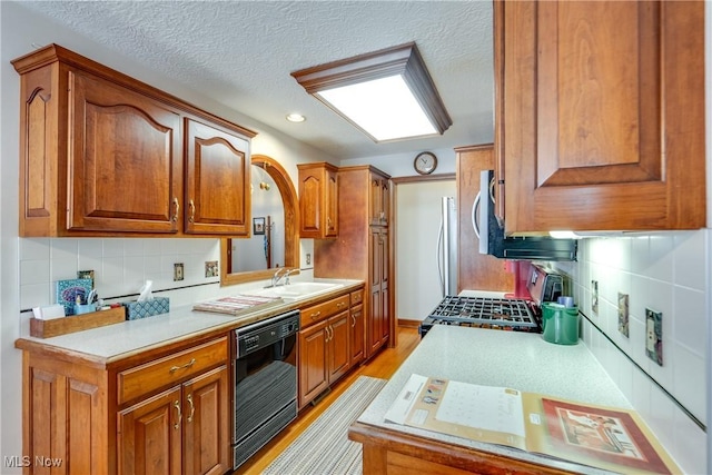 kitchen with light hardwood / wood-style floors, stove, black dishwasher, and decorative backsplash