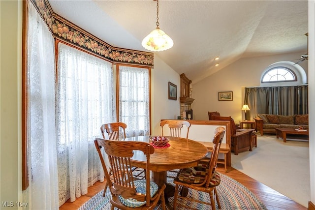 dining area with a textured ceiling, vaulted ceiling, ceiling fan, and wood-type flooring