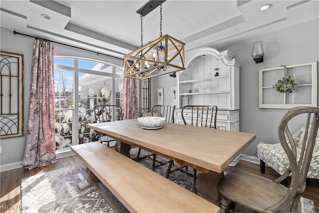 dining space featuring a raised ceiling, a chandelier, and dark hardwood / wood-style floors