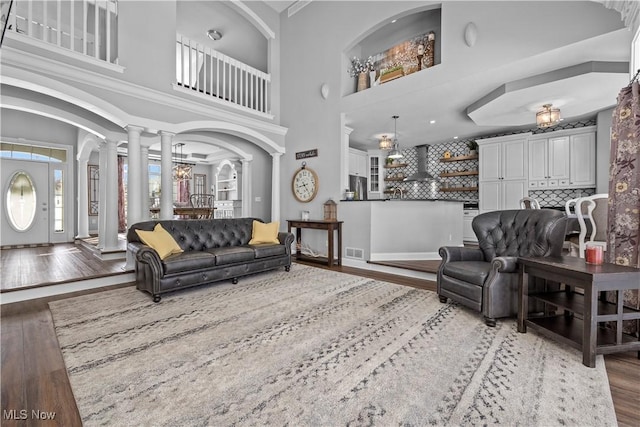 living room with hardwood / wood-style flooring, decorative columns, and a high ceiling