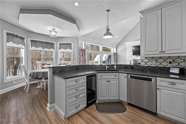 kitchen featuring dark stone countertops, vaulted ceiling, beverage cooler, stainless steel dishwasher, and gray cabinets