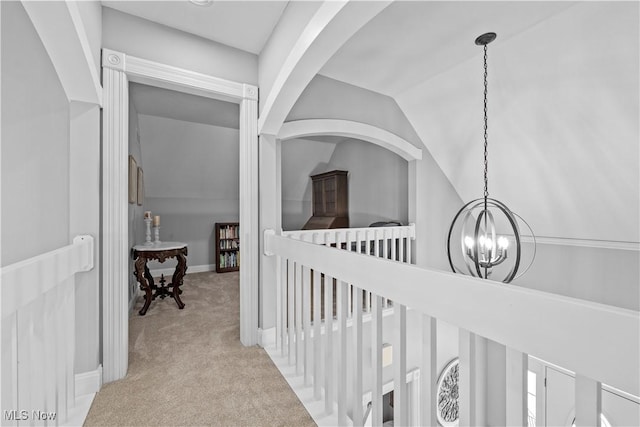 hall featuring light carpet, an inviting chandelier, and lofted ceiling