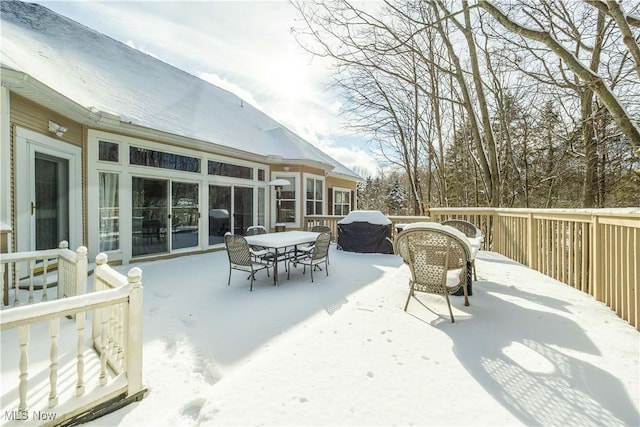 snow covered patio featuring area for grilling and a wooden deck