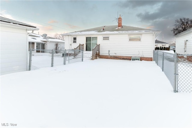 snow covered rear of property featuring central air condition unit