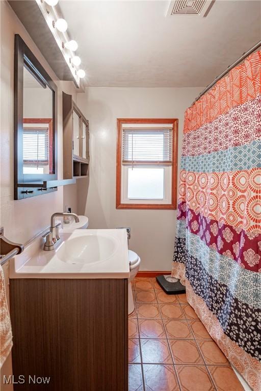 bathroom featuring toilet, vanity, and a healthy amount of sunlight