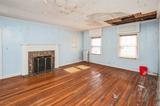 unfurnished living room featuring crown molding, a tiled fireplace, wood-type flooring, and radiator