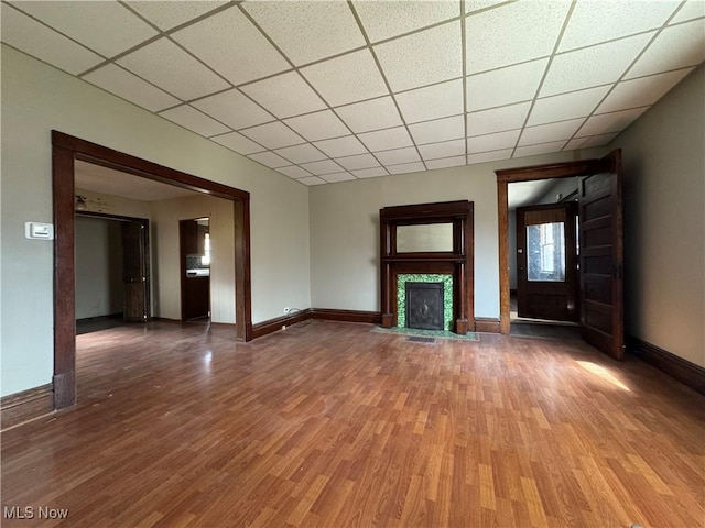 unfurnished living room with a tile fireplace, dark hardwood / wood-style floors, and a drop ceiling