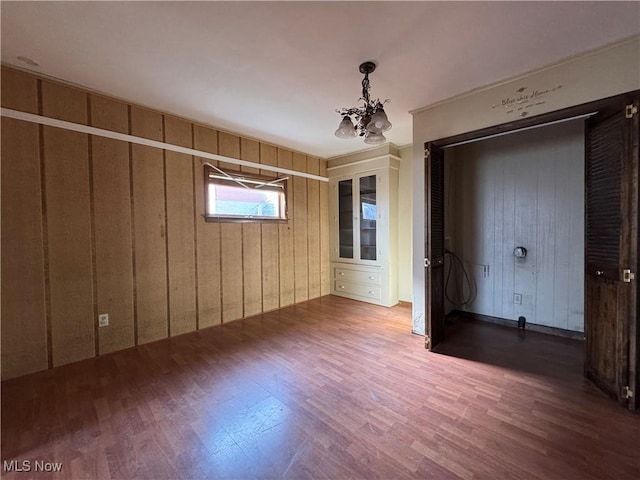 unfurnished bedroom with hardwood / wood-style floors and a notable chandelier