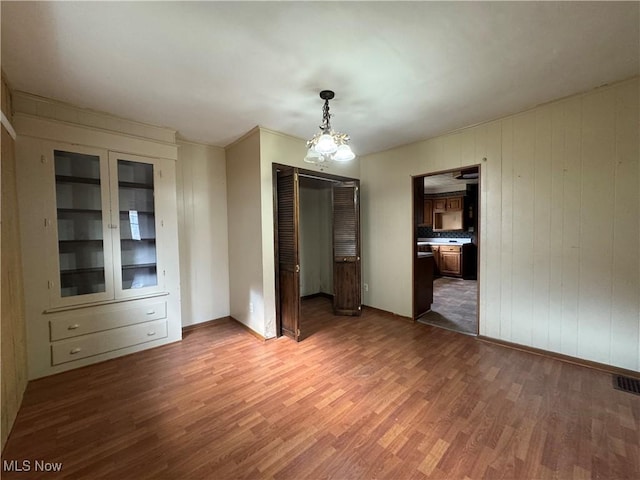 unfurnished dining area with a notable chandelier and dark wood-type flooring