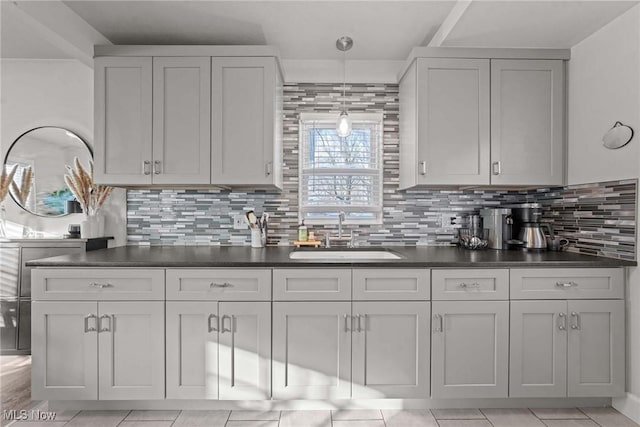 kitchen featuring sink, hanging light fixtures, white cabinetry, and backsplash