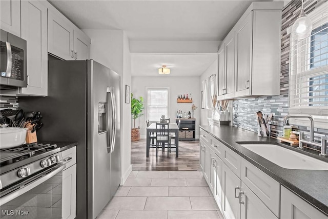 kitchen with sink, appliances with stainless steel finishes, white cabinets, and light tile patterned floors