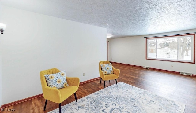 sitting room featuring dark hardwood / wood-style flooring and a textured ceiling