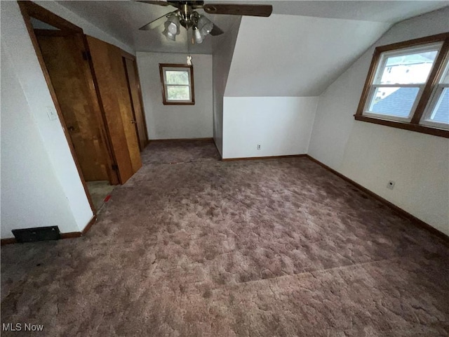 additional living space featuring lofted ceiling, dark carpet, and ceiling fan