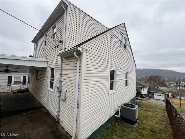 view of side of property with central AC unit and a lawn