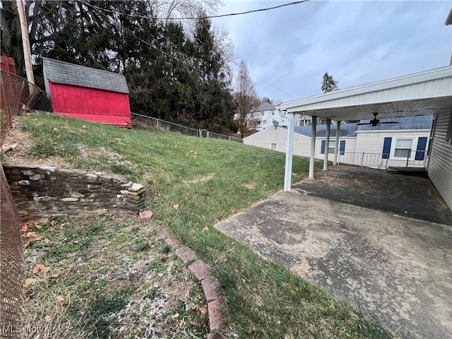 view of yard featuring a storage unit, ceiling fan, and a carport