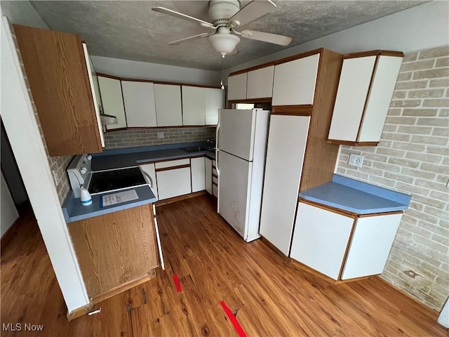 kitchen with white fridge, stainless steel electric range, white cabinets, and light hardwood / wood-style flooring