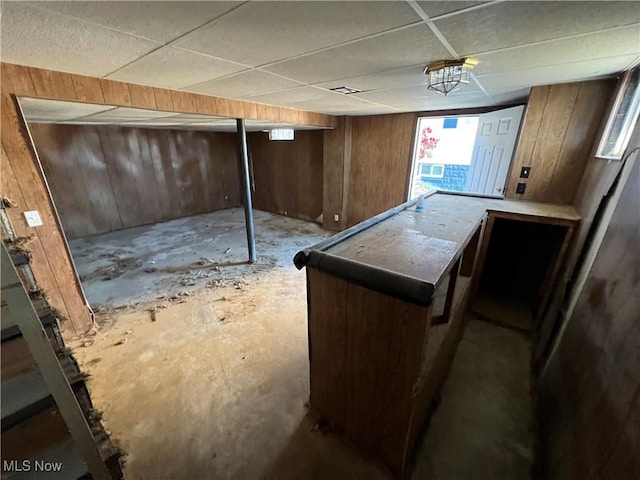 basement with wood walls and a drop ceiling