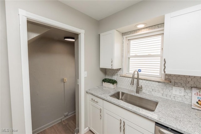 kitchen with a sink, white cabinets, tasteful backsplash, and wood finished floors