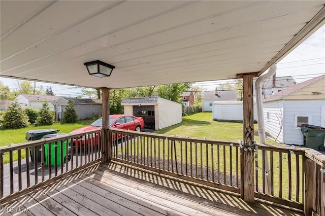 deck featuring an outdoor structure, a lawn, and a residential view