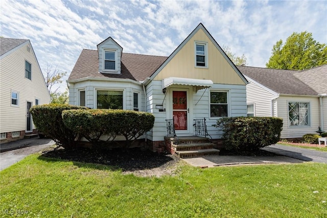 view of front of house with a front yard, a shingled roof, entry steps, and board and batten siding