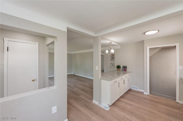 bar area featuring light wood-style flooring, a chandelier, and baseboards