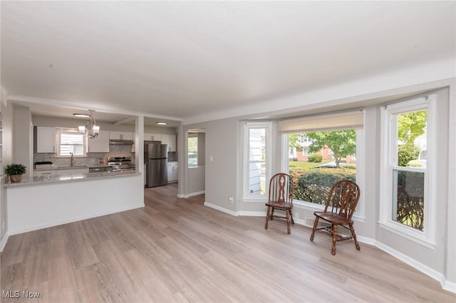 sitting room with a chandelier, light wood-style floors, and baseboards