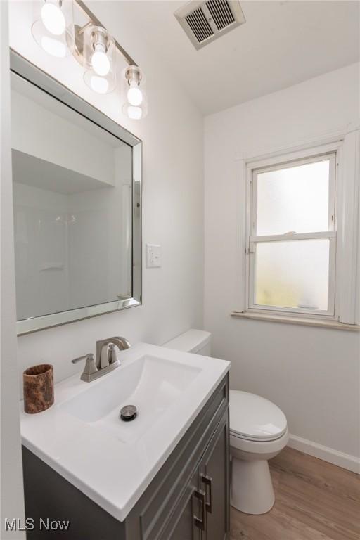 bathroom featuring vanity, toilet, wood finished floors, and baseboards