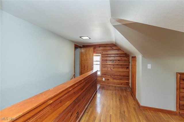 bonus room with light wood-style flooring and vaulted ceiling