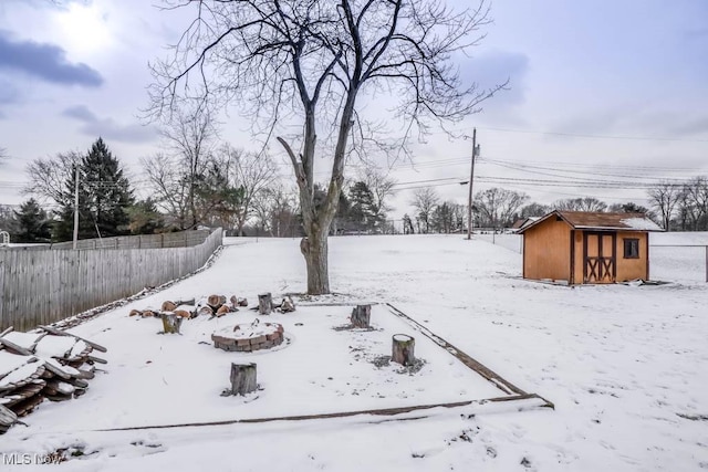 yard covered in snow with a storage unit and a fire pit