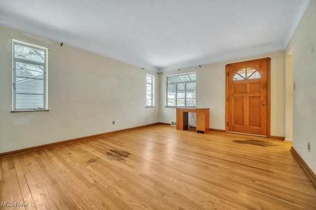 unfurnished living room featuring light wood-style floors, baseboards, and ornamental molding