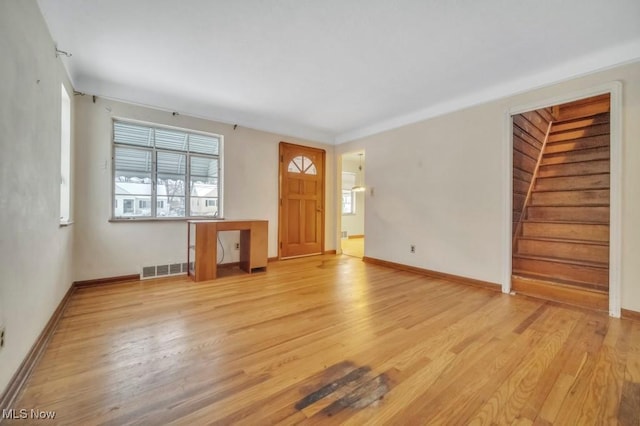 unfurnished living room featuring visible vents, light wood-style flooring, and baseboards