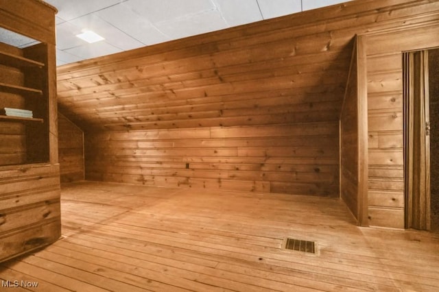 bonus room featuring lofted ceiling, wooden walls, wood ceiling, light wood-style floors, and a sauna