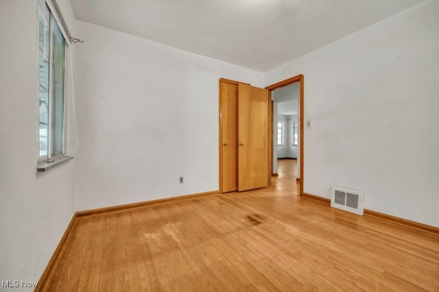 unfurnished room with visible vents, light wood-style flooring, and baseboards