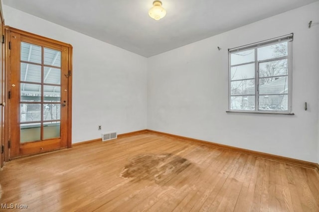 spare room with light wood-style floors, visible vents, and baseboards