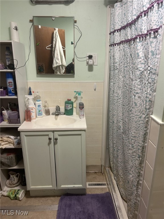 bathroom featuring tile walls, curtained shower, and vanity