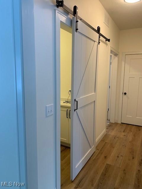 1775 Green Rd, Madison, OH 44057 - corridor featuring a barn door and light wood-style flooring