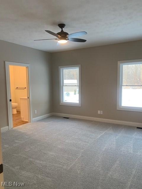 unfurnished room featuring baseboards, carpet, a ceiling fan, and visible vents