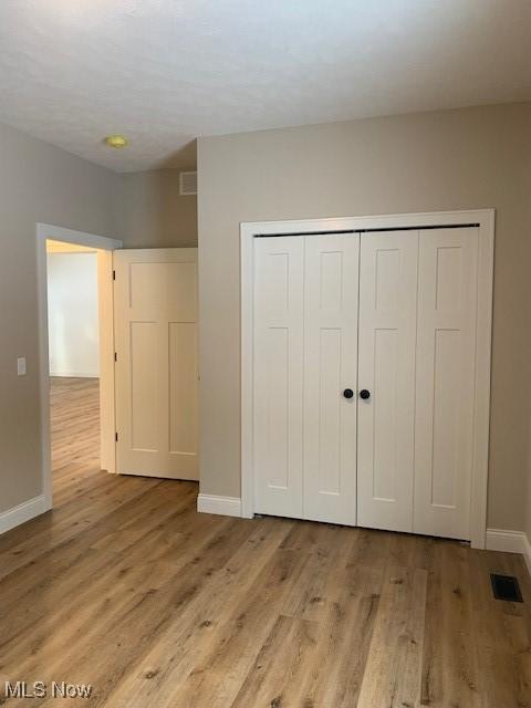 1775 Green Rd, Madison, OH 44057 - unfurnished bedroom with baseboards, a closet, and light wood-style flooring
