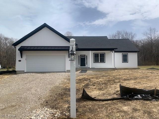 view of front of home featuring an attached garage, metal roof, a standing seam roof, and dirt driveway