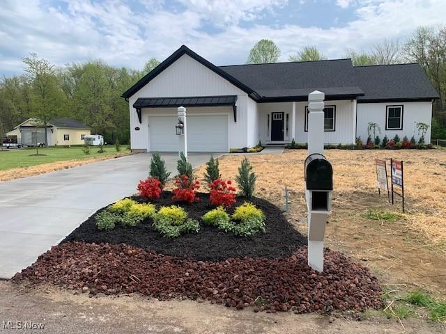 single story home featuring a garage, covered porch, a standing seam roof, and driveway