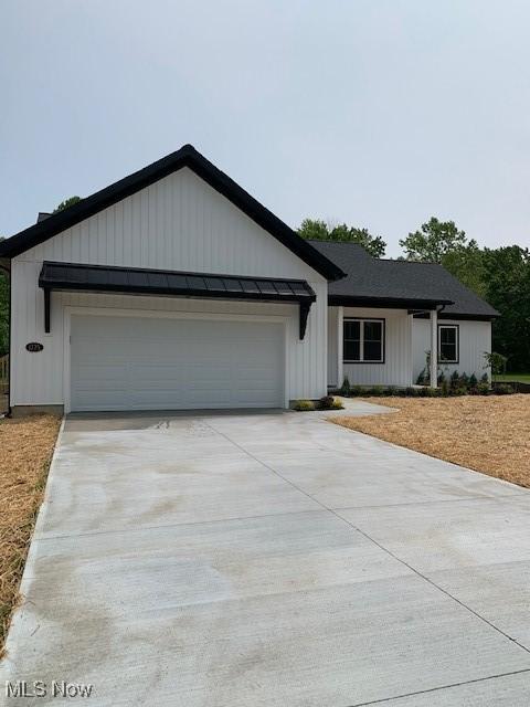 1775 Green Rd, Madison, OH 44057 - modern farmhouse with driveway, a garage, a standing seam roof, and board and batten siding