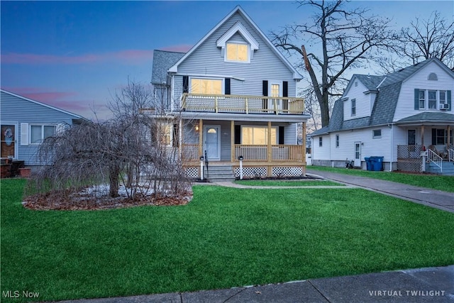 view of front of home featuring a porch, a balcony, and a lawn