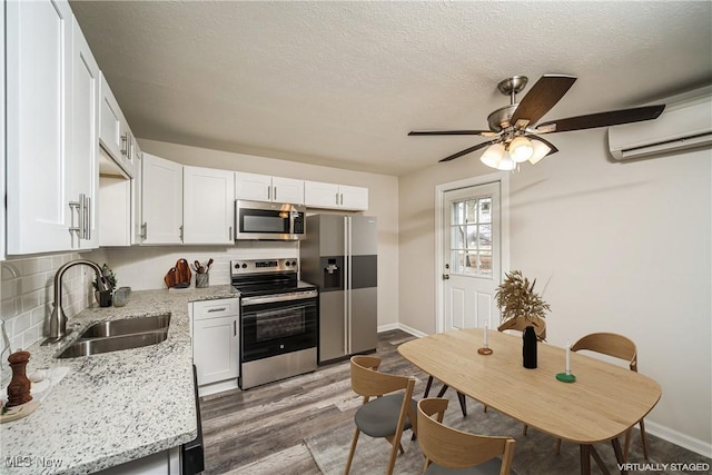 kitchen featuring appliances with stainless steel finishes, sink, white cabinetry, and light stone countertops