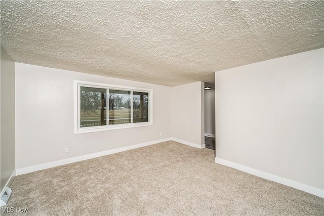 spare room featuring light carpet and a textured ceiling