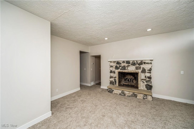 unfurnished living room featuring a stone fireplace, light carpet, and a textured ceiling